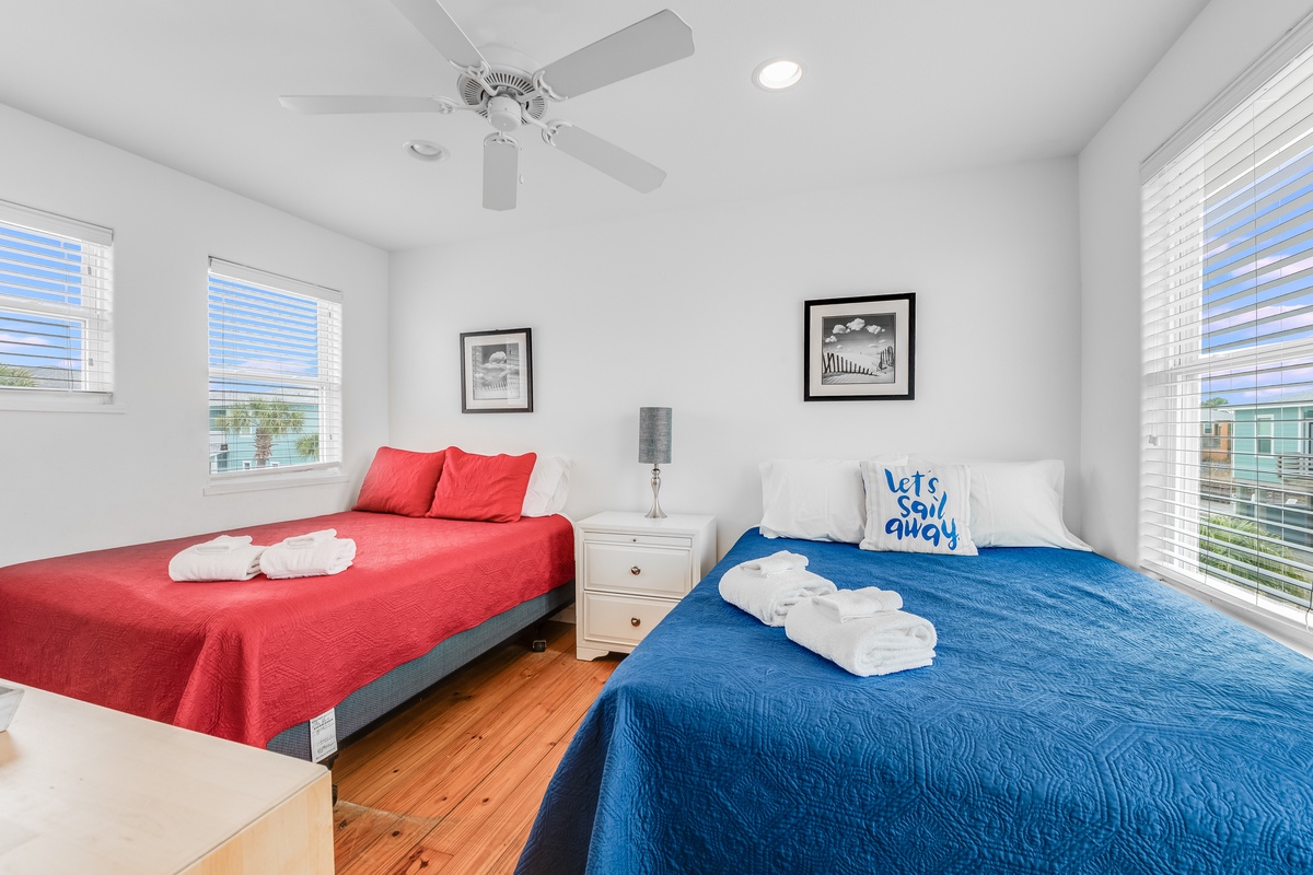 Drift into restful sleep in this bright full bedroom where colorful bedding meets coastal comfort, complete with fresh towels and gentle ceiling fan.