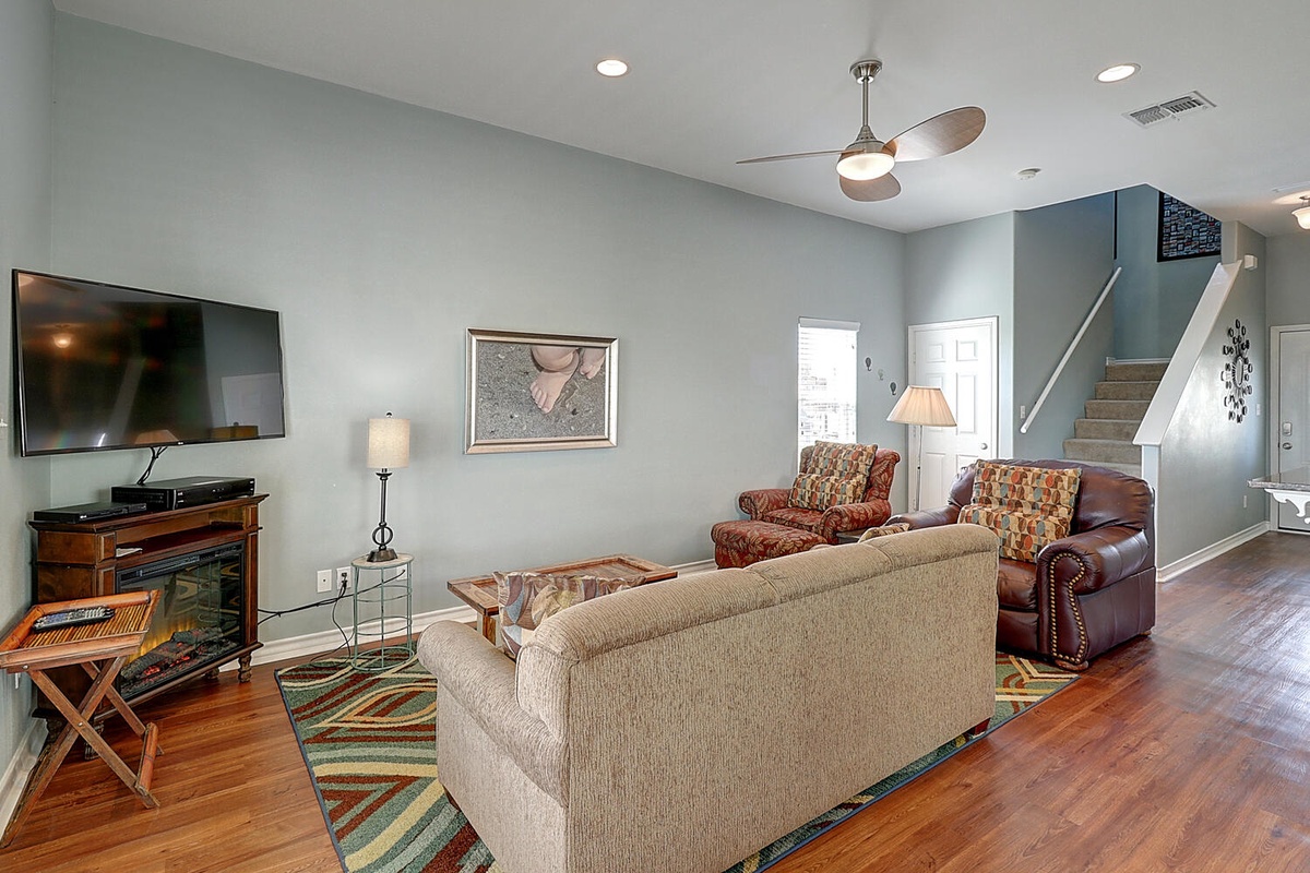 Unwind in your spacious living room with cozy seating, entertainment center, and warm wood floors creating the perfect home base.