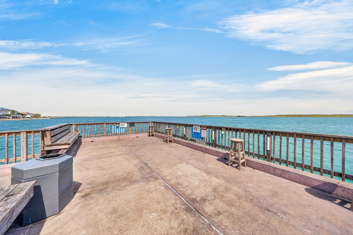 A scenic waterfront pier offering tranquil views of turquoise waters and distant shorelines, with bench seating perfect for watching the day unfold.