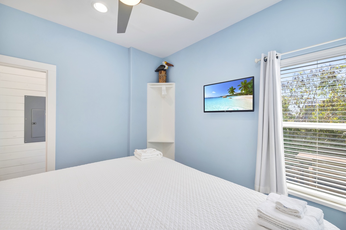 Drift off in this serene blue bedroom where tropical breezes flow through your window and soft linens await your arrival.