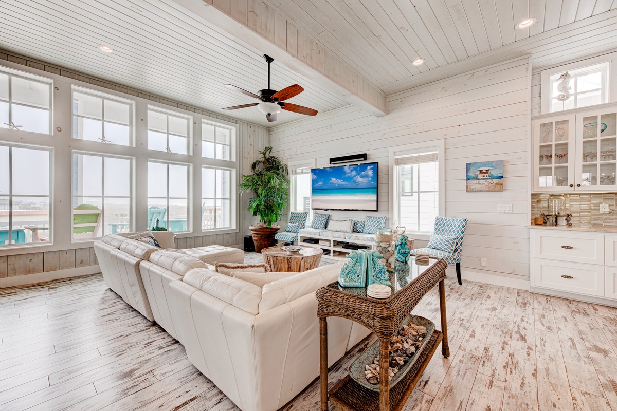 Sink into plush sofas in your bright, beachy living space where coastal charm meets modern comfort with ocean views and ceiling fan breezes.