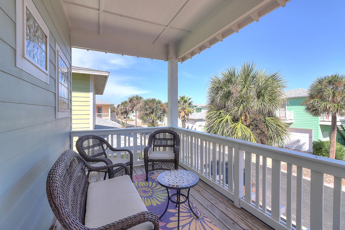 Your private balcony invites morning coffee and sunset conversations with comfortable wicker seating overlooking tropical palms.