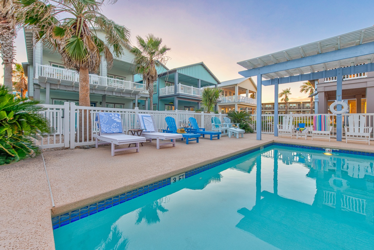 A tropical paradise pool deck with vibrant blue water, comfortable loungers, and swaying palms creating your perfect vacation escape.