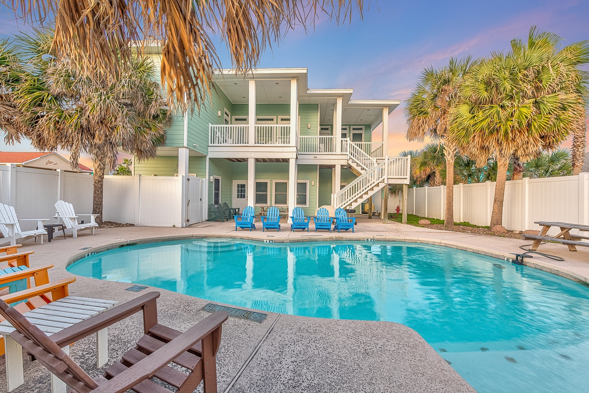 Spacious coastal home with private pool, surrounded by swaying palm trees and comfortable outdoor seating for the perfect beach vacation retreat.