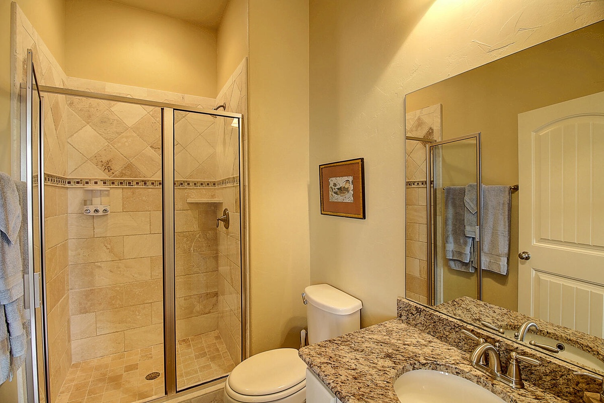 Refresh in your elegant private bathroom featuring a spacious walk-in shower with beautiful tiling and granite countertops.