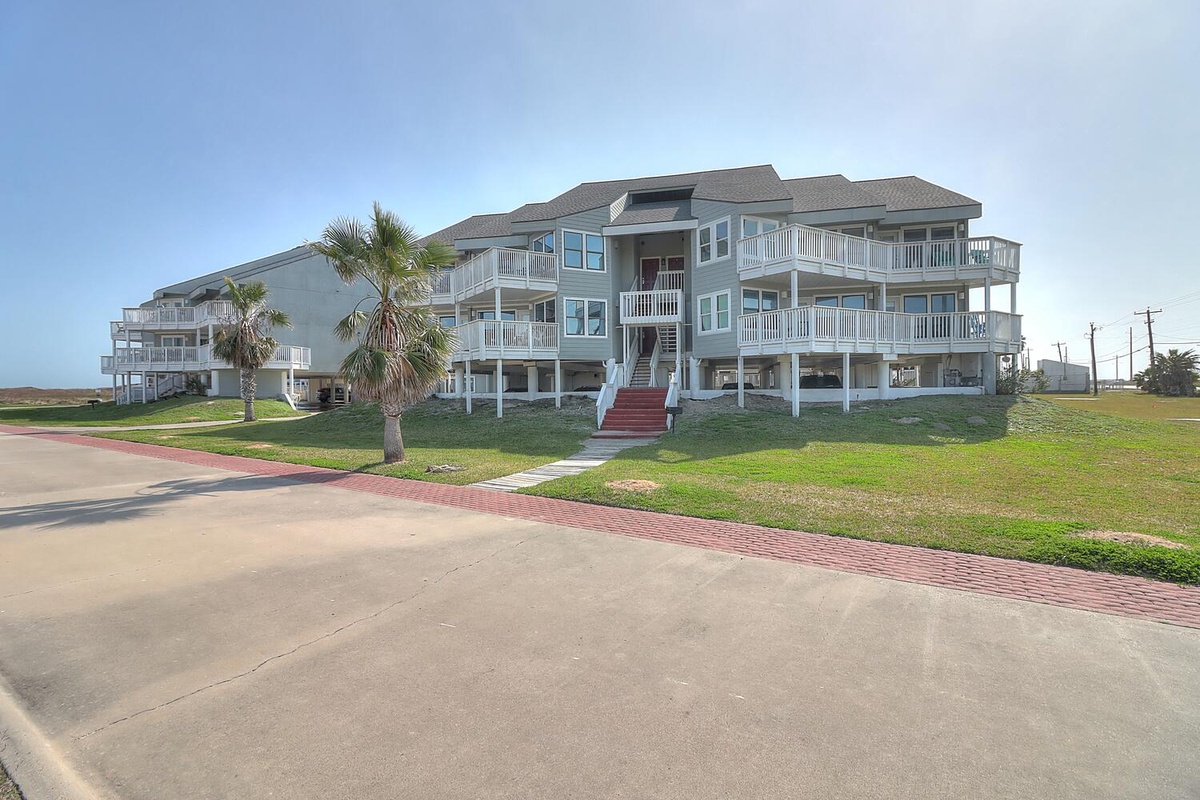 Modern beachfront property featuring multiple balconies and coastal access along a quiet residential street.