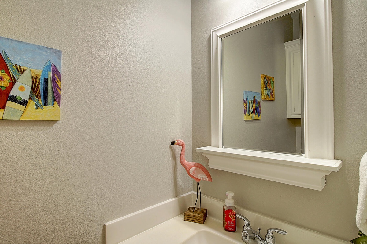 Freshen up in your charming bathroom featuring coastal artwork and whimsical flamingo touches that add personality to your daily routine.