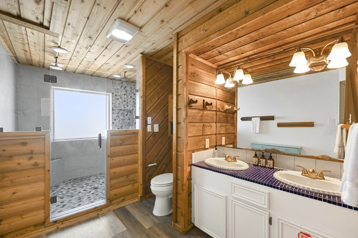 Step into your private retreat with a spacious walk-in shower, dual vanities, and warm wood accents that blend rustic charm with modern comfort.