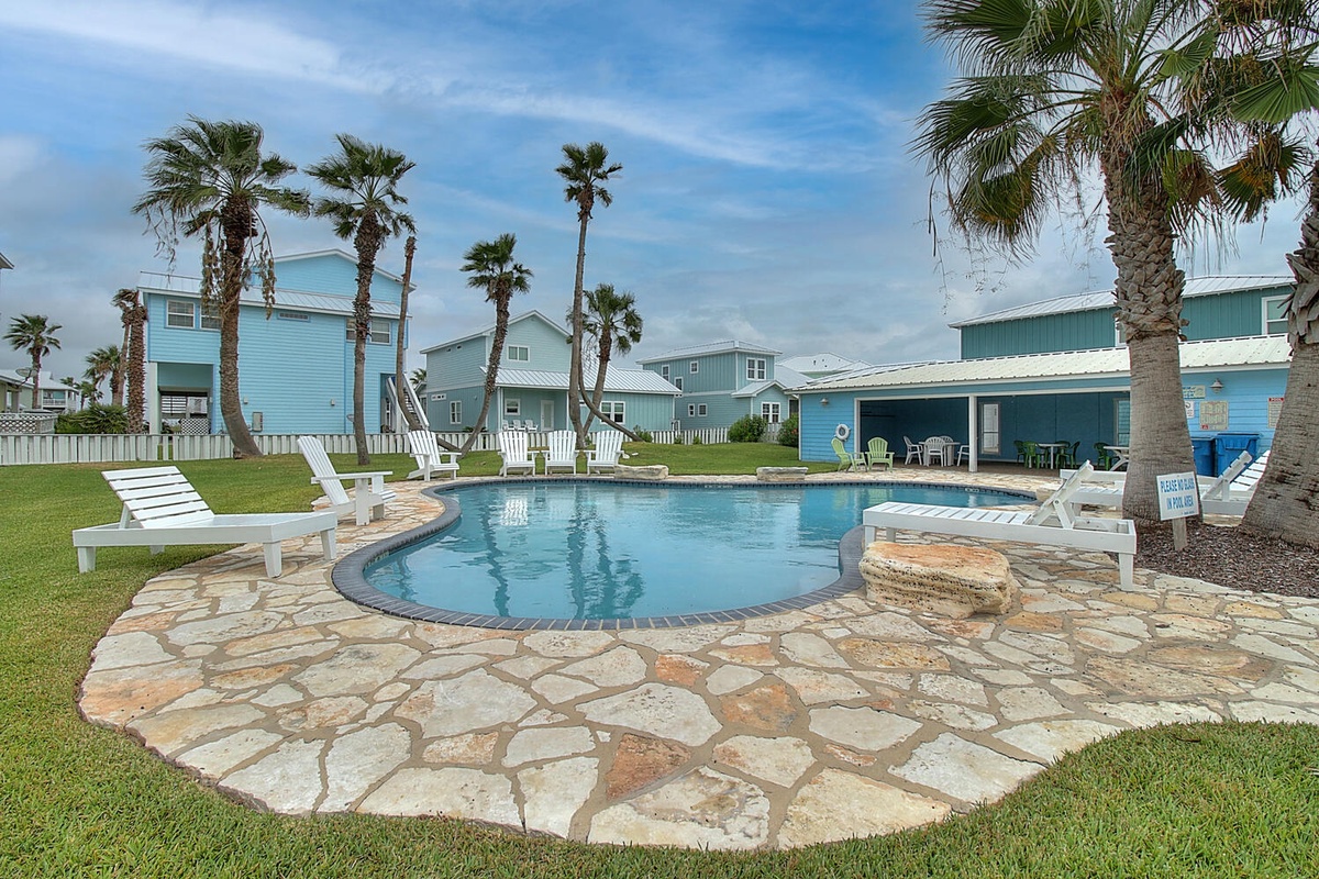 Dive into your tropical paradise with this sparkling pool surrounded by swaying palms and colorful beach houses.
