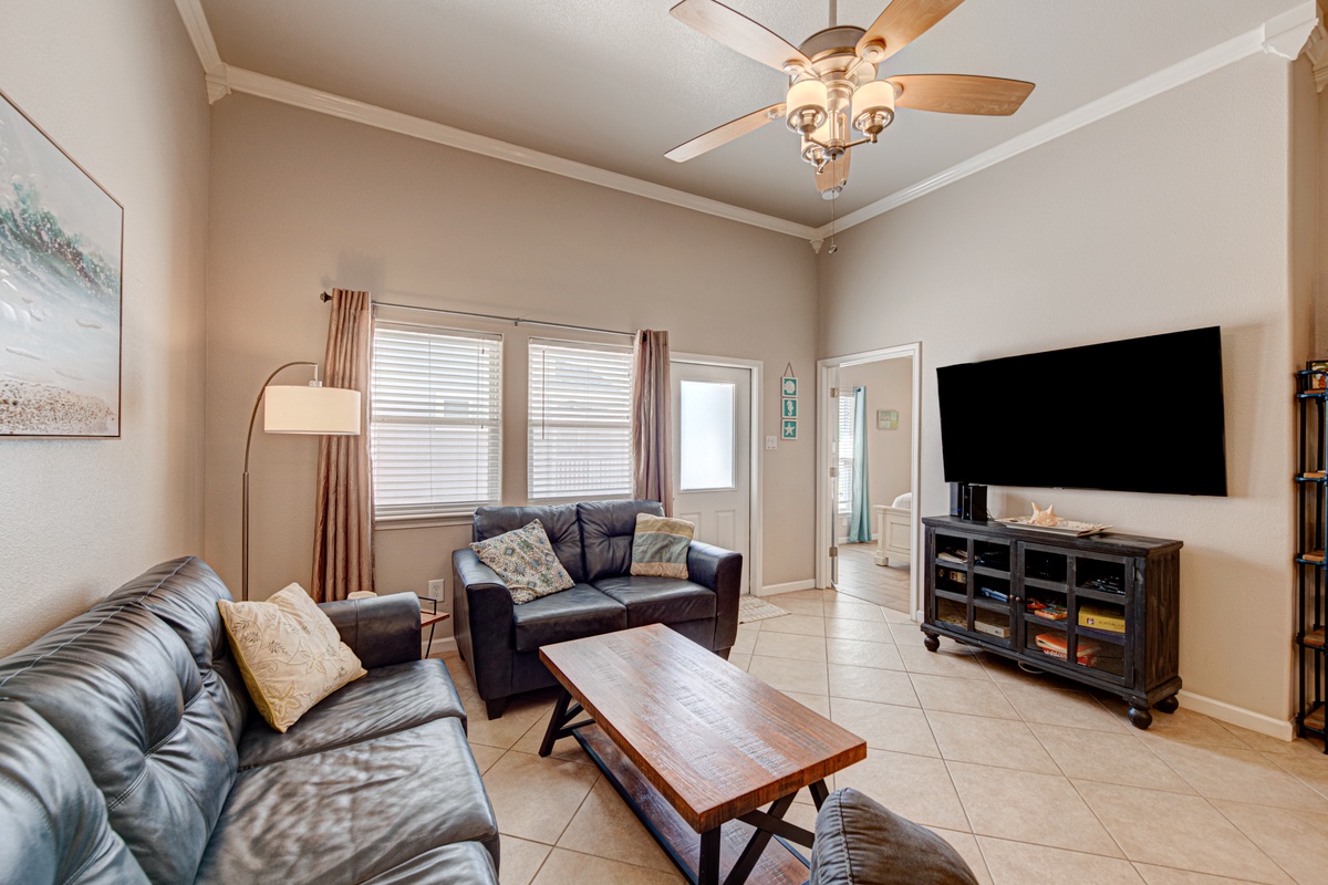 Relax in your spacious living room with plush leather seating, entertainment center, and gentle ceiling fan keeping you comfortable.