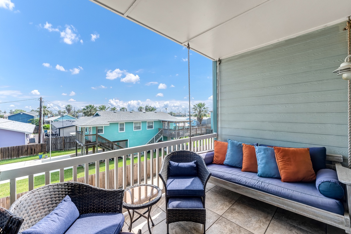 Relax on your private balcony with comfortable seating and colorful cushions while enjoying peaceful neighborhood views.