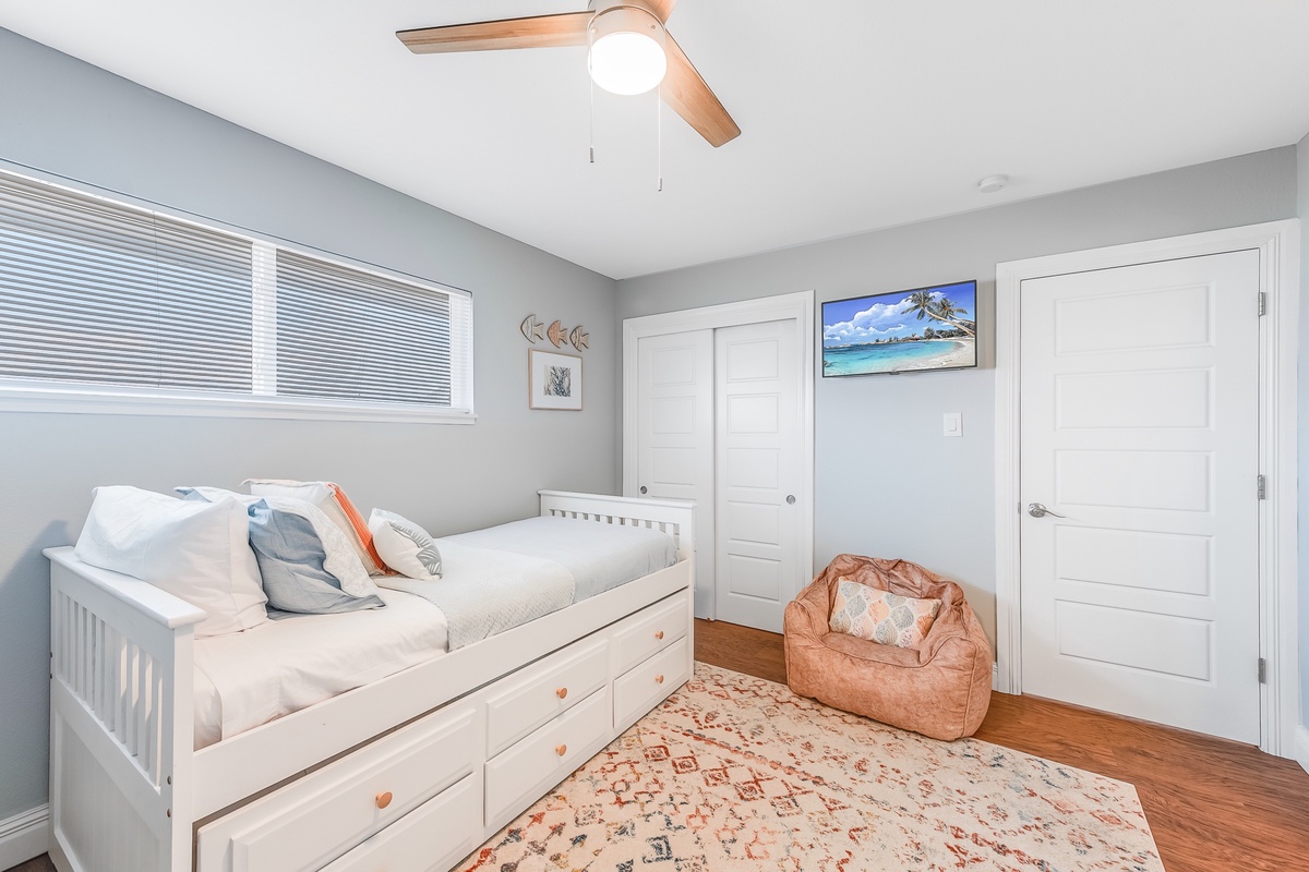 Unwind in your bright coastal bedroom with a comfy daybed, ceiling fan keeping you cool, and tropical art inspiring beach dreams.