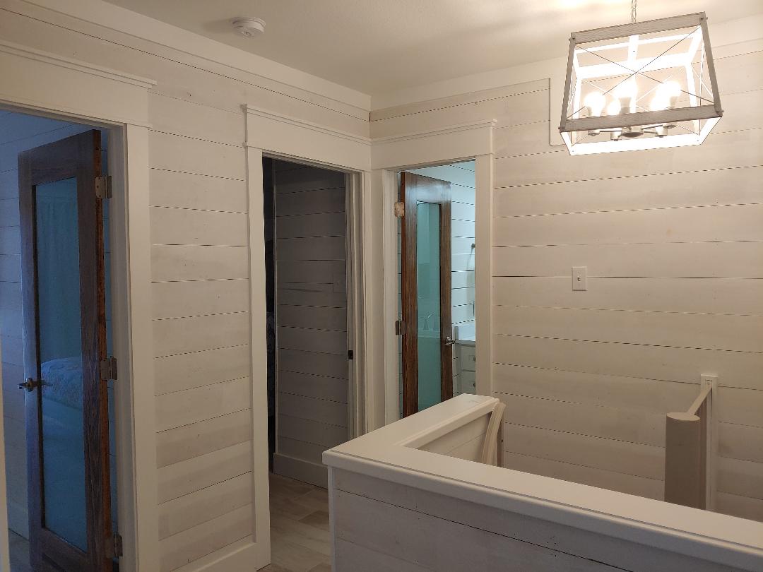 Crisp white shiplap walls and modern glass lighting create your peaceful upstairs retreat, with multiple rooms awaiting your arrival.