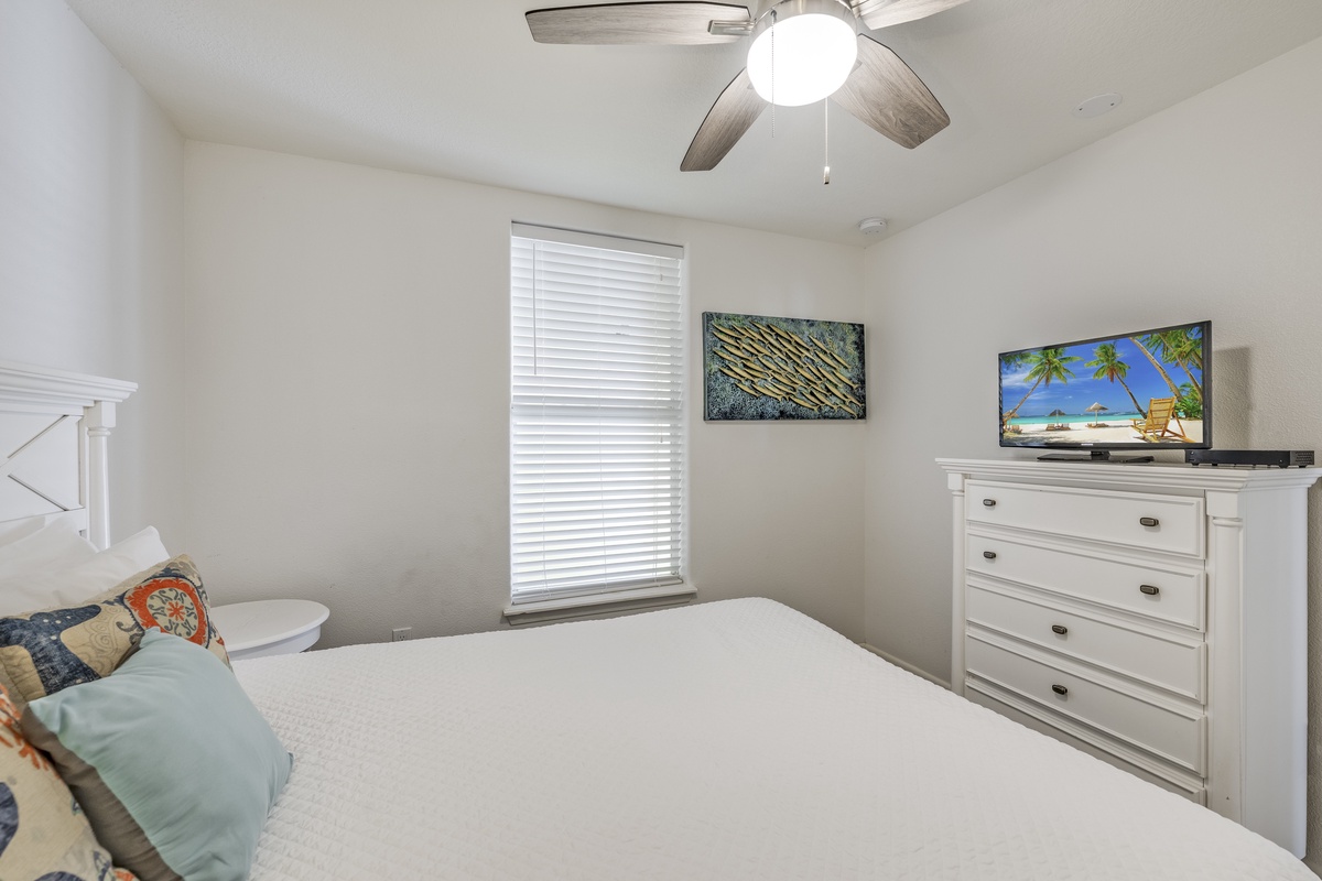 Drift off in your cozy bedroom with a plush bed, ceiling fan, tropical touches, and entertainment at your fingertips for the ultimate vacation relaxation.