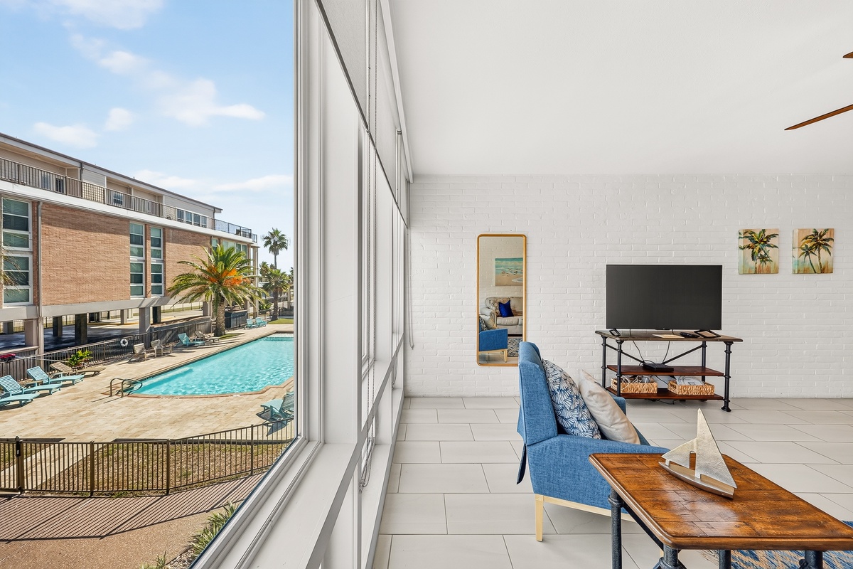 Sink into the blue couch and enjoy the warmth as light floods through floor-to-ceiling windows overlooking the sparkling pool and palm-studded courtyard just steps away.