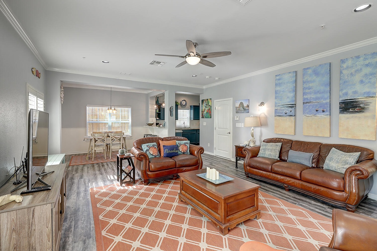 Sink into plush leather sofas in your spacious living room, where coastal artwork and warm lighting create the perfect atmosphere for relaxation.