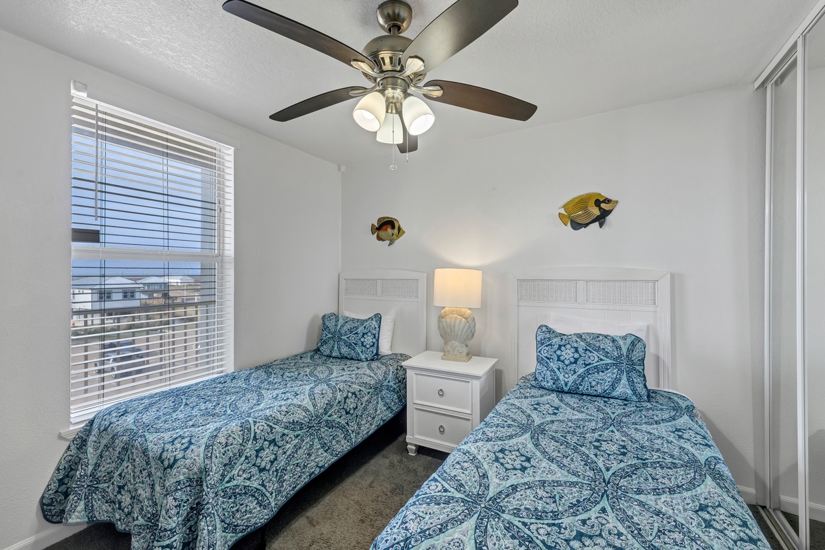 Settle into this cheerful guest bedroom featuring two twin beds, coastal décor, and plenty of natural light.