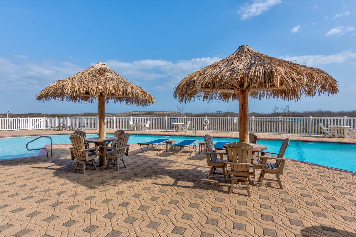 Soak in the pool under tropical tiki huts and lounge on sunny pavers as you gaze across open horizons from this resort-style retreat.