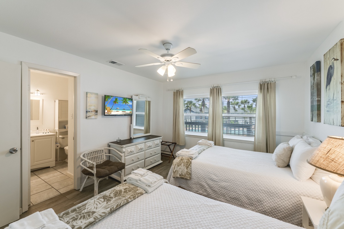Sink into plush beds in this bright, airy bedroom where coastal charm meets comfort. Palm views from your window and a private ensuite await your arrival.