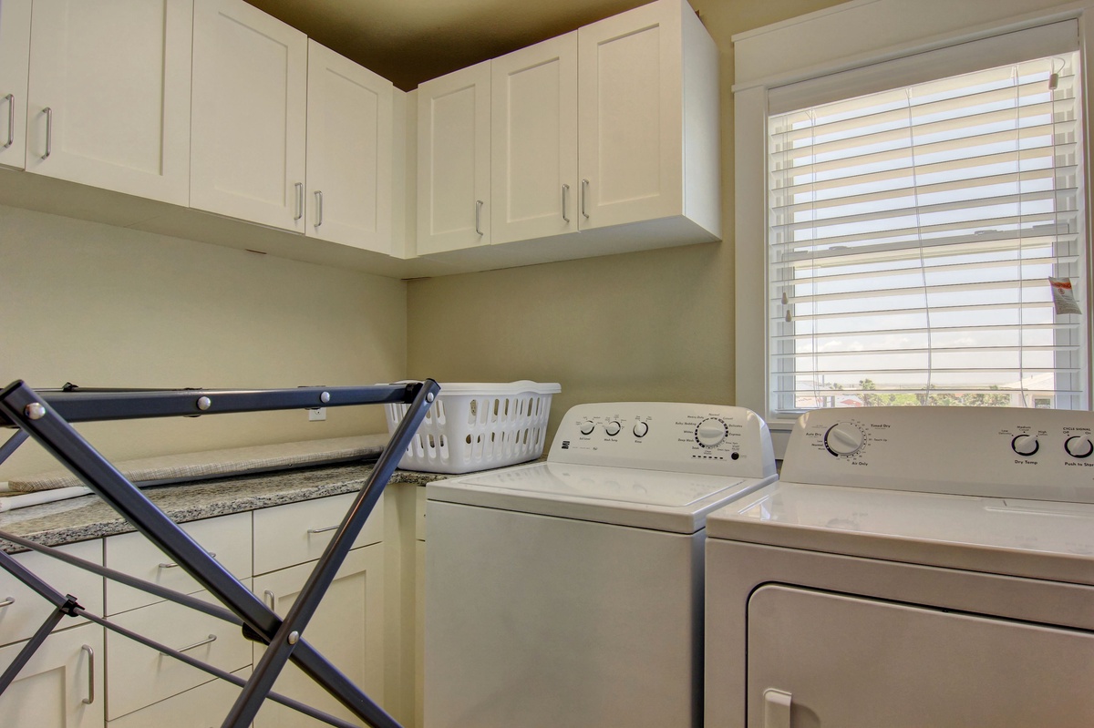 Your laundry routine becomes effortless with this well-organized space featuring full-size washer and dryer, ample cabinet storage, and convenient folding area.