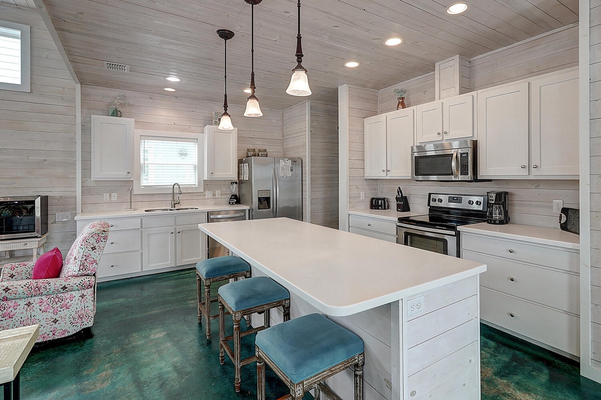 Your bright kitchen features modern appliances, a spacious island with seating, and charming shiplap walls that create a cozy coastal vibe.