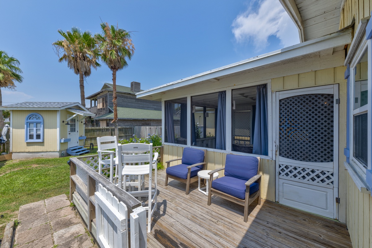 A coastal property featuring beachside bungalows with decks and outdoor seating, surrounded by palm trees in a tranquil neighborhood setting under blue skies.