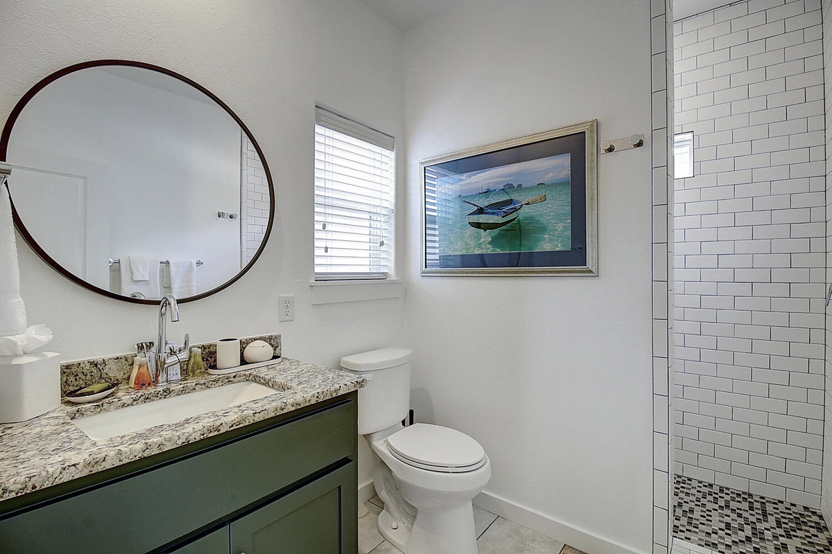 Step into your private sanctuary featuring elegant subway tile shower, granite vanity, and charming coastal artwork for peaceful morning routines.