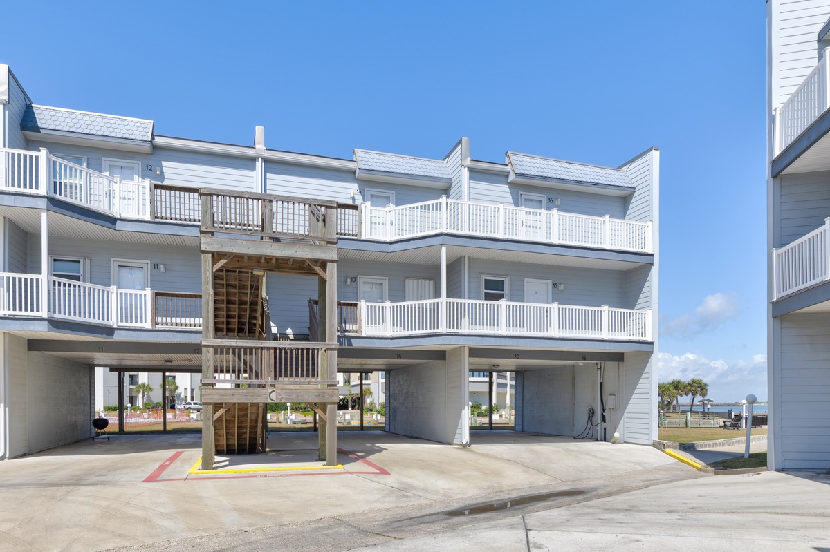 Coastal vacation rental building featuring multiple levels with balconies and convenient ground-level parking spaces.