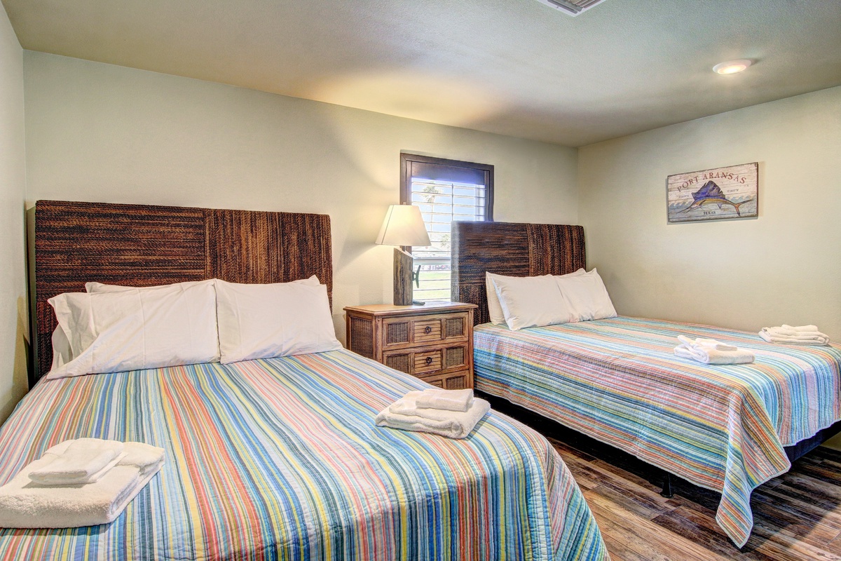 Your coastal bedroom features twin beds with colorful linens and wicker headboards, creating a breezy beach retreat.