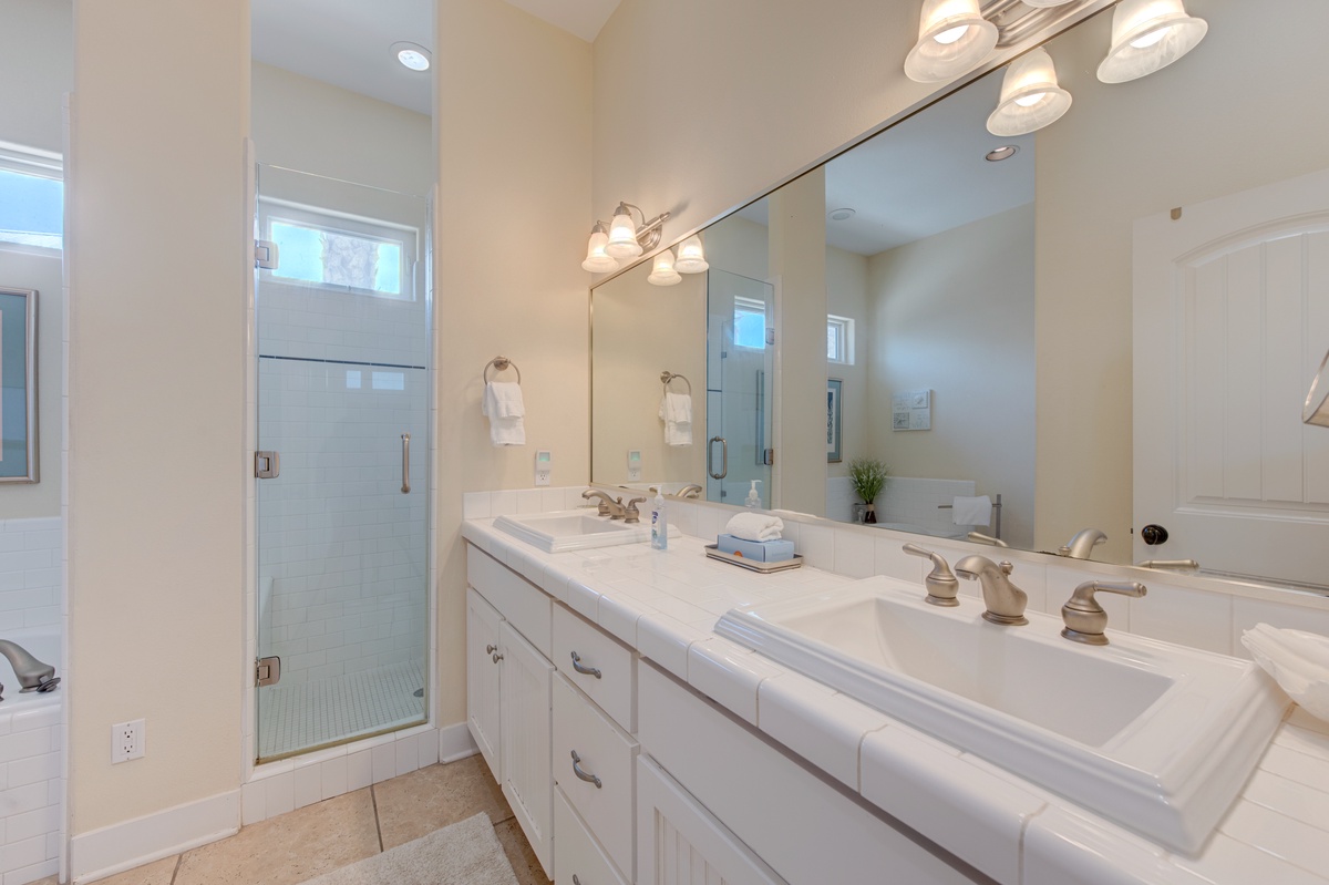 Step into your elegant bathroom retreat with dual sinks, pristine countertops, and a spacious glass shower waiting for your relaxation.