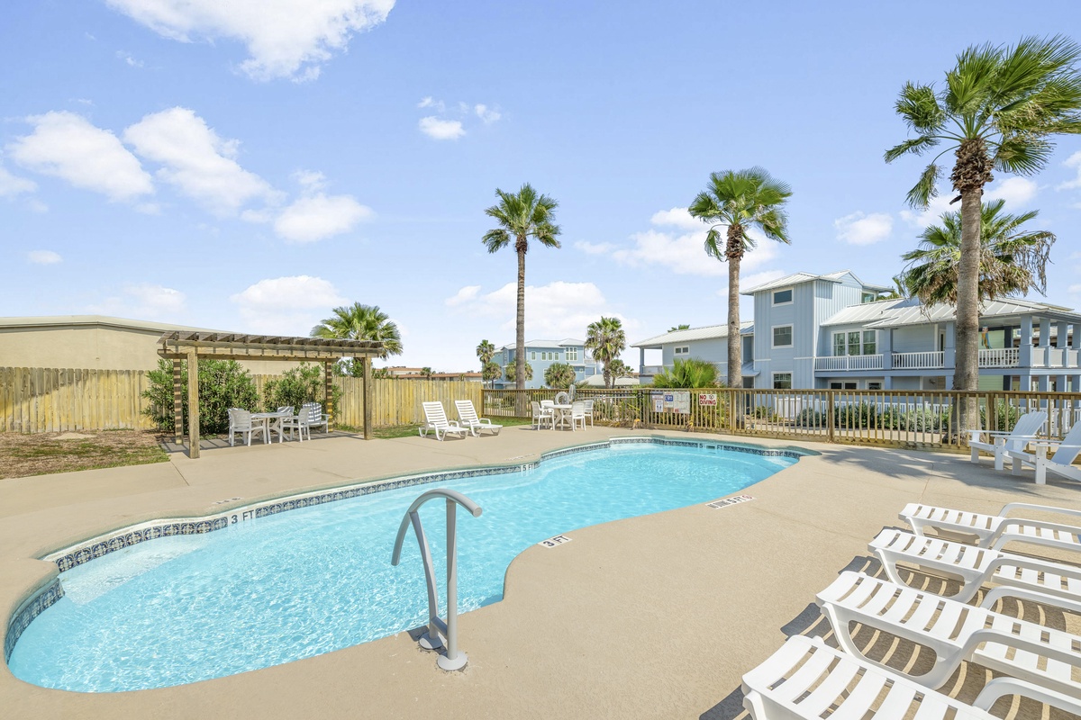 Dive into your own tropical oasis with this sparkling pool surrounded by swaying palms and comfortable loungers.