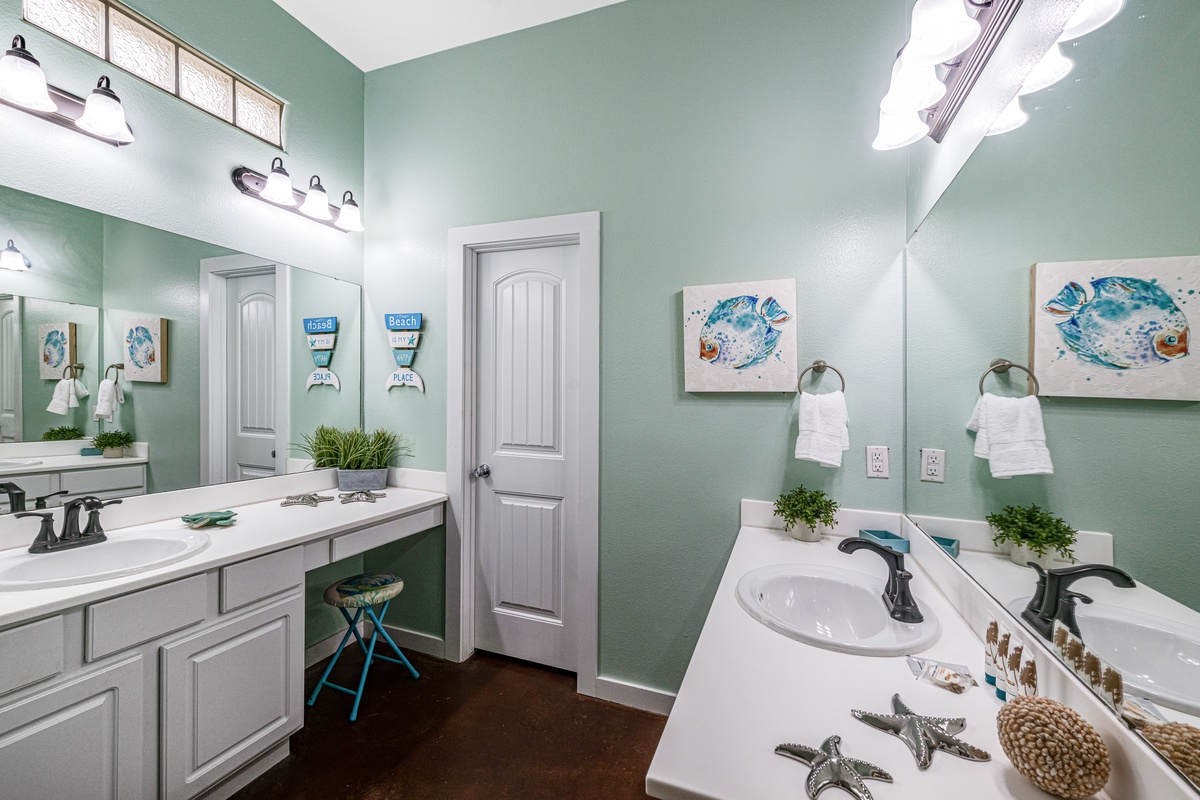 Refresh in your coastal-themed bathroom with dual vanities, charming sea-inspired artwork, and thoughtful amenities creating a serene spa-like atmosphere.