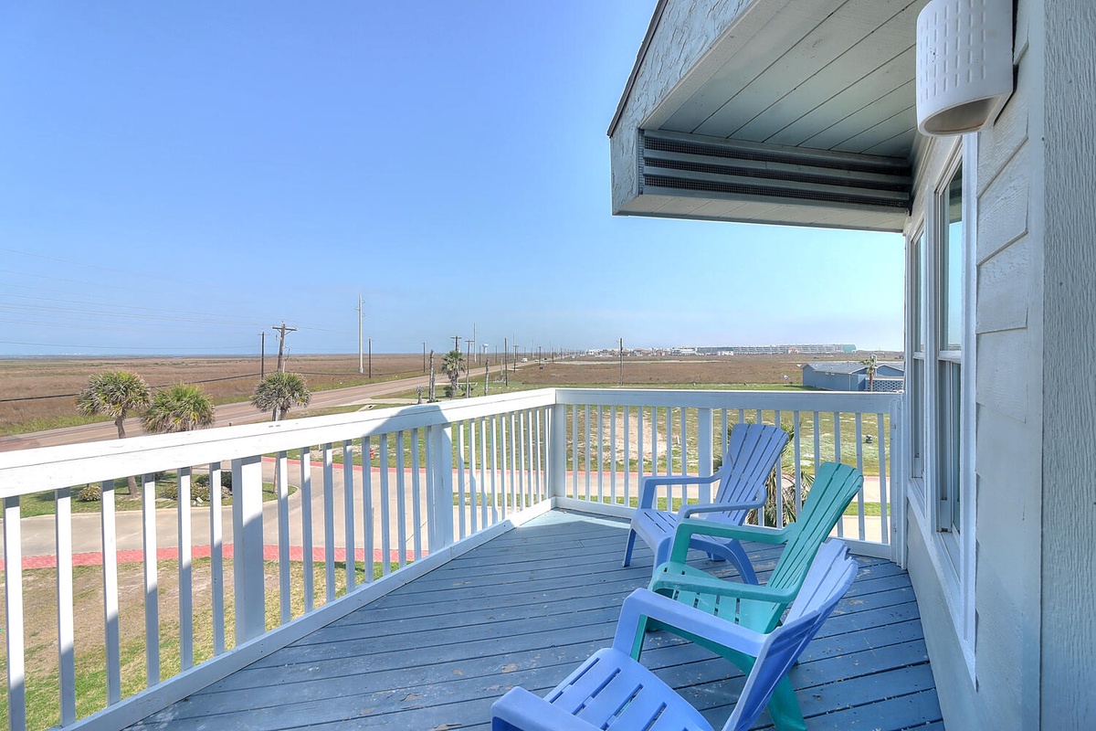 Bright coastal balcony with colorful Adirondack chairs where you can relax while taking in sweeping views of the surrounding landscape.