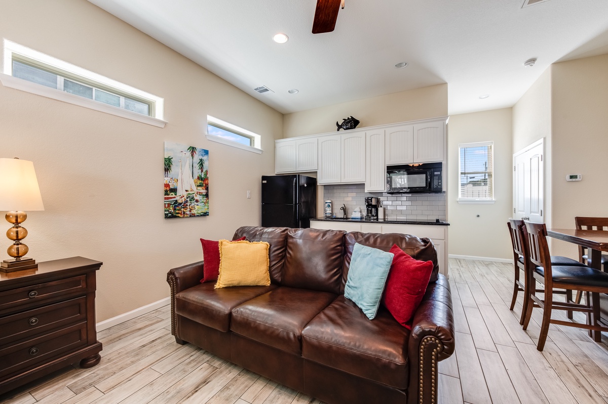 Relax in your open-concept living space featuring rich leather seating, exposed beams, and a fully-equipped kitchen ready for your culinary adventures.