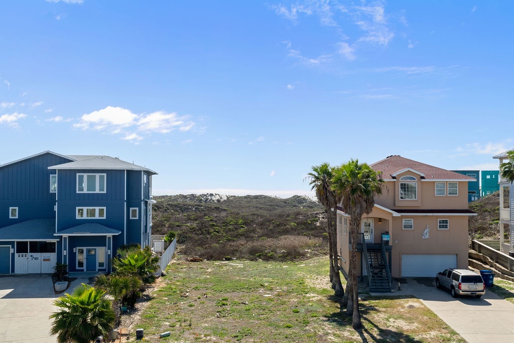 Beachside homes nestled among rolling hills and palm trees create a peaceful coastal neighborhood setting.