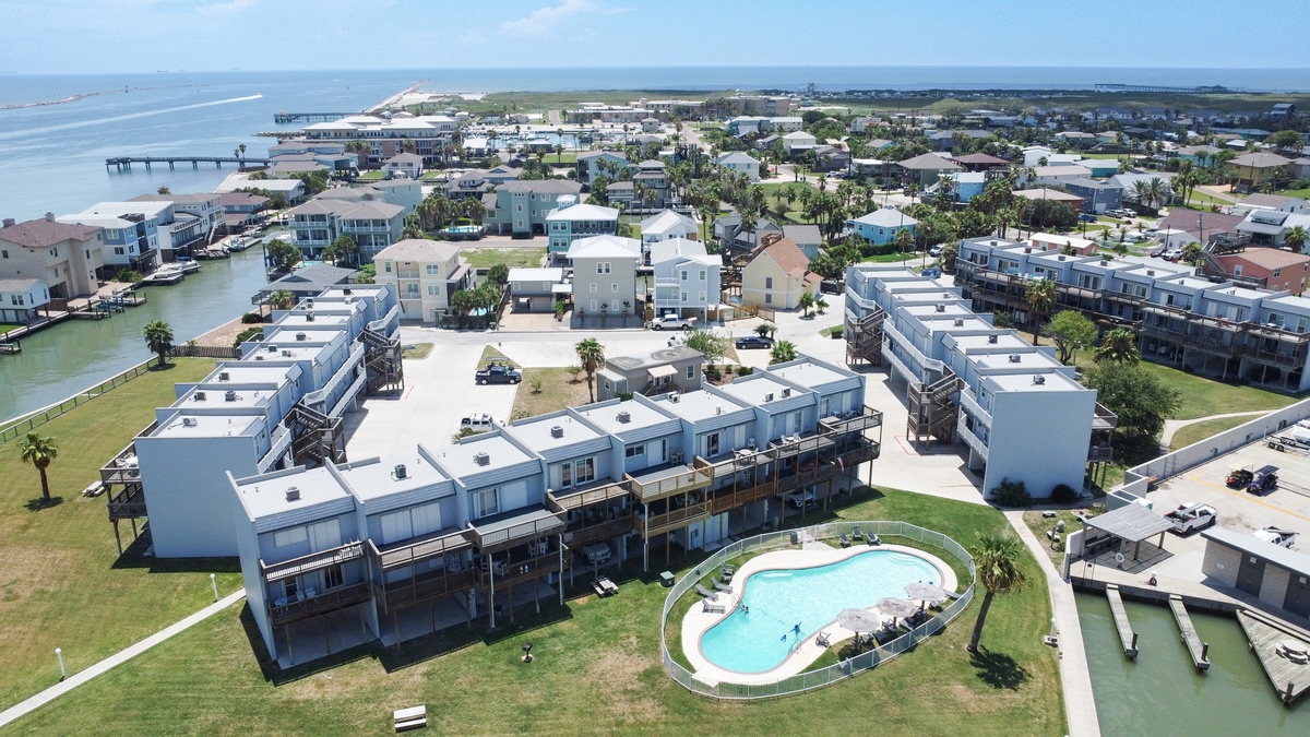 Modern beachfront property complex featuring swimming pool and marina access in coastal community setting.