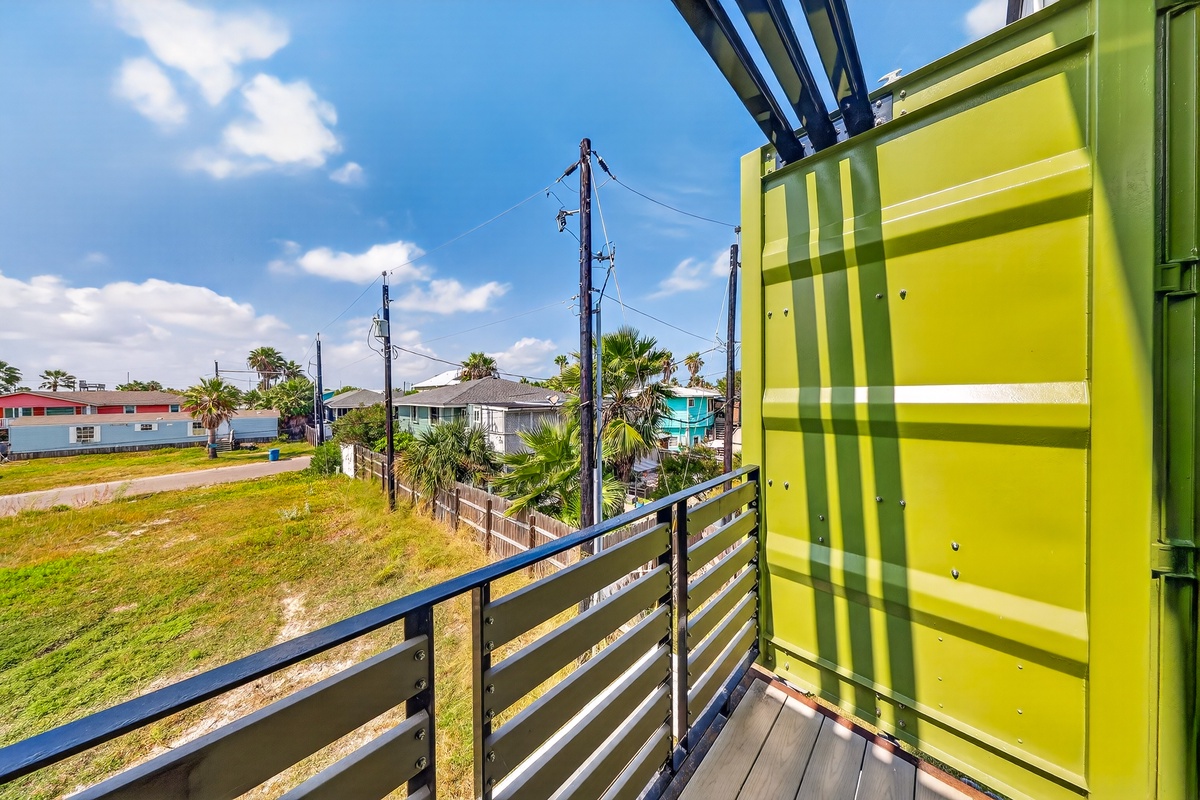 The property sits in a quiet coastal neighborhood with palm trees and colorful homes nearby, offering a relaxed, beachy atmosphere.