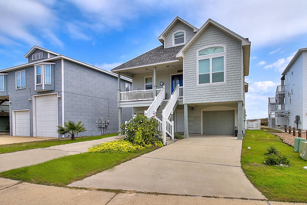 Charming coastal rental home with covered porch, garage parking, and beautifully landscaped yard in quiet residential neighborhood.