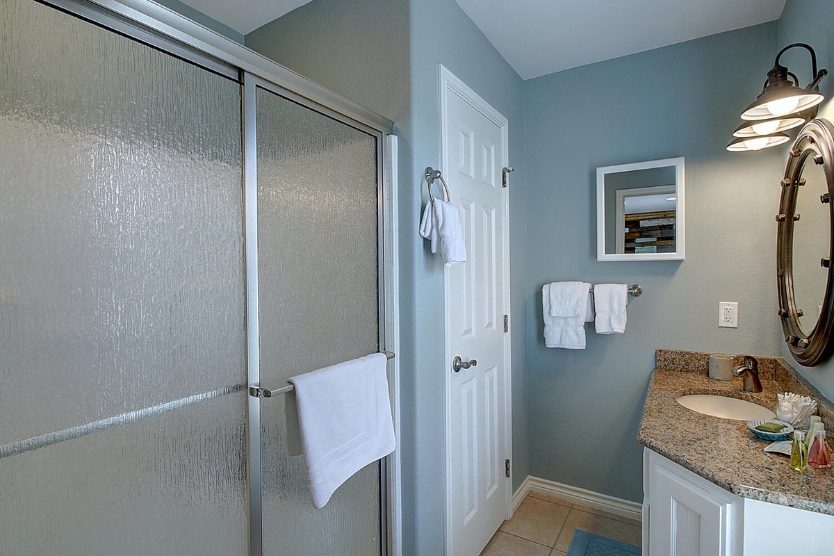 Step into your spa-like bathroom with spacious glass shower, granite vanity, and soft coastal colors that create a calming retreat.