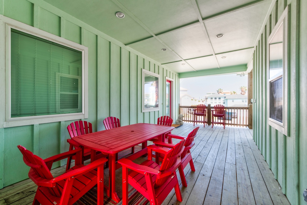 Your vibrant covered deck awaits with cheerful red dining furniture, perfect for enjoying morning coffee or evening meals outdoors.