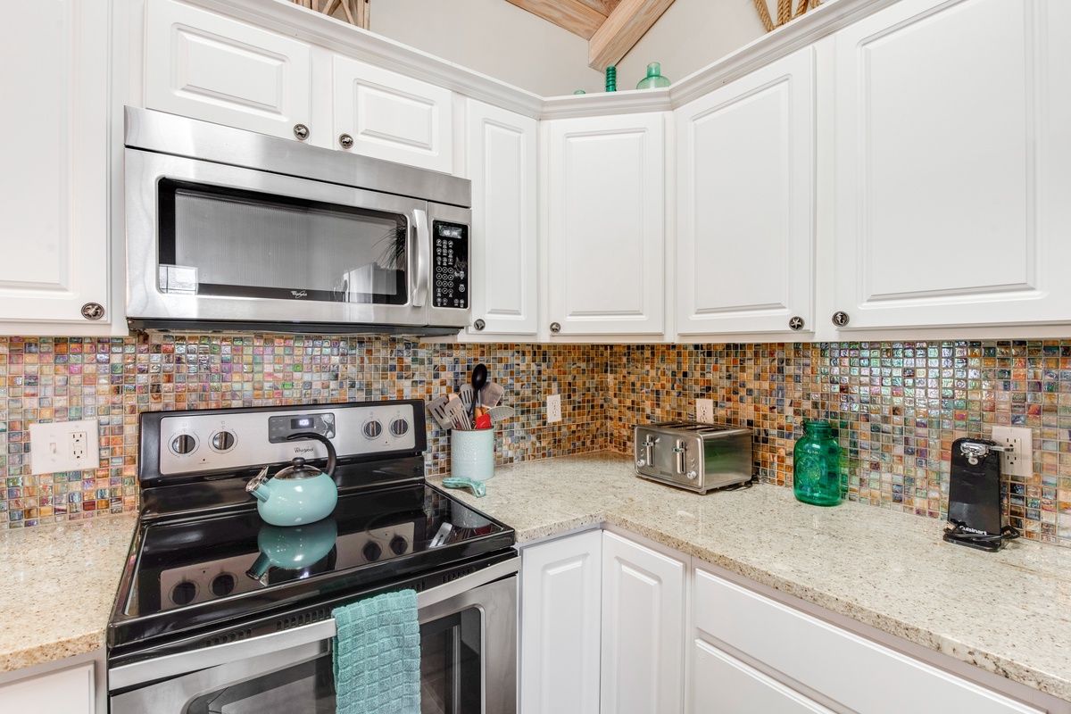 Your fully equipped kitchen features sparkling white cabinets, granite countertops, and a stunning mosaic backsplash that catches the light beautifully.