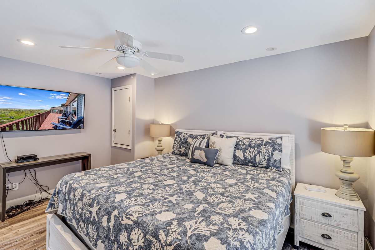 Drift off in your coastal-themed bedroom with ocean-inspired bedding, gentle ceiling fan, and TV for relaxing evenings.