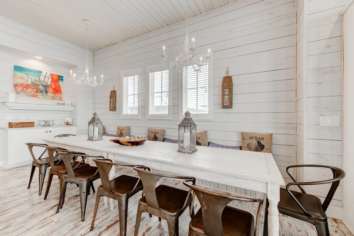 Gather around this stunning coastal dining table where shiplap walls and crystal chandeliers create your perfect space for memorable meals together.