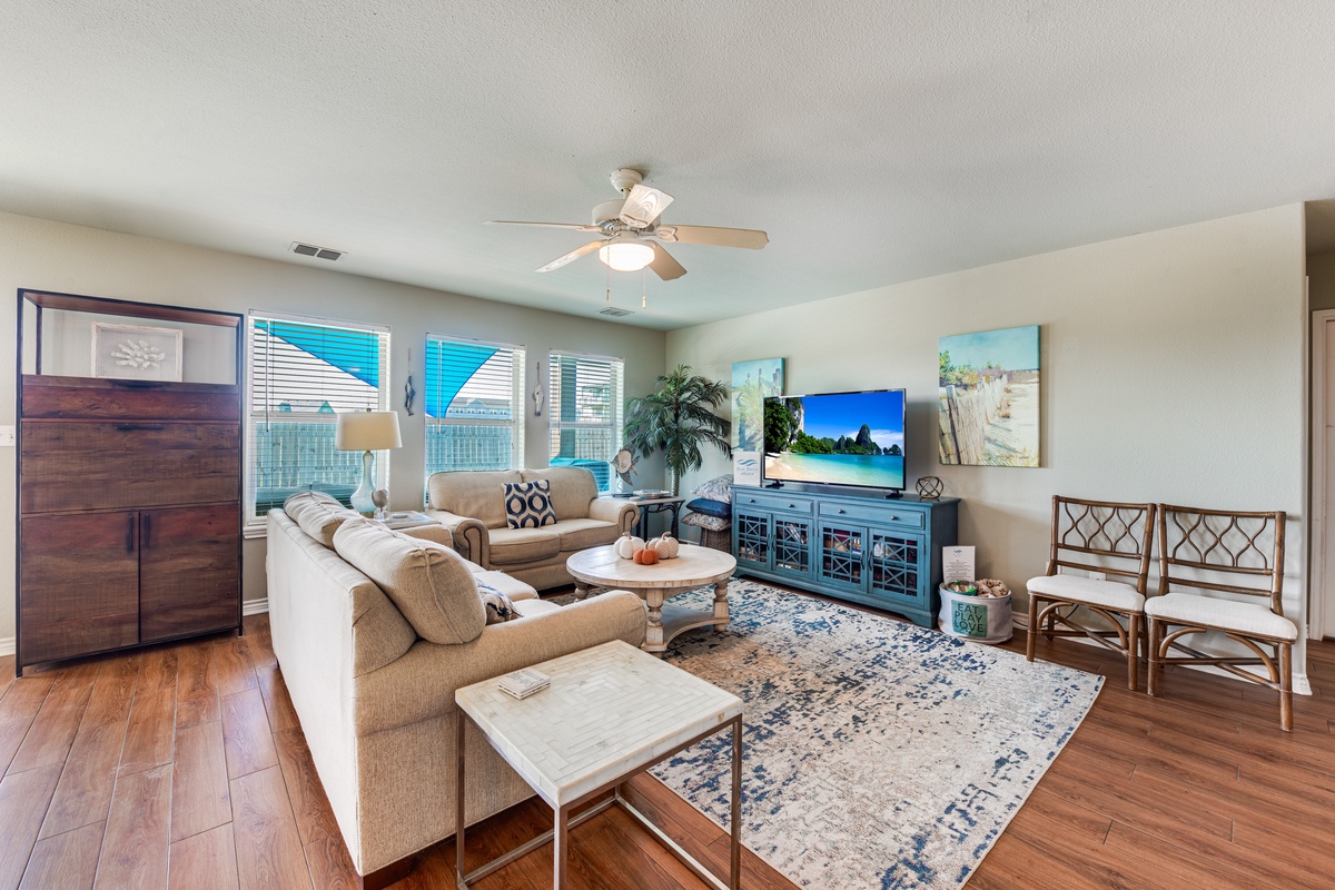 Relax in your bright, spacious living room with comfortable seating, ceiling fan, and entertainment center for perfect vacation downtime.