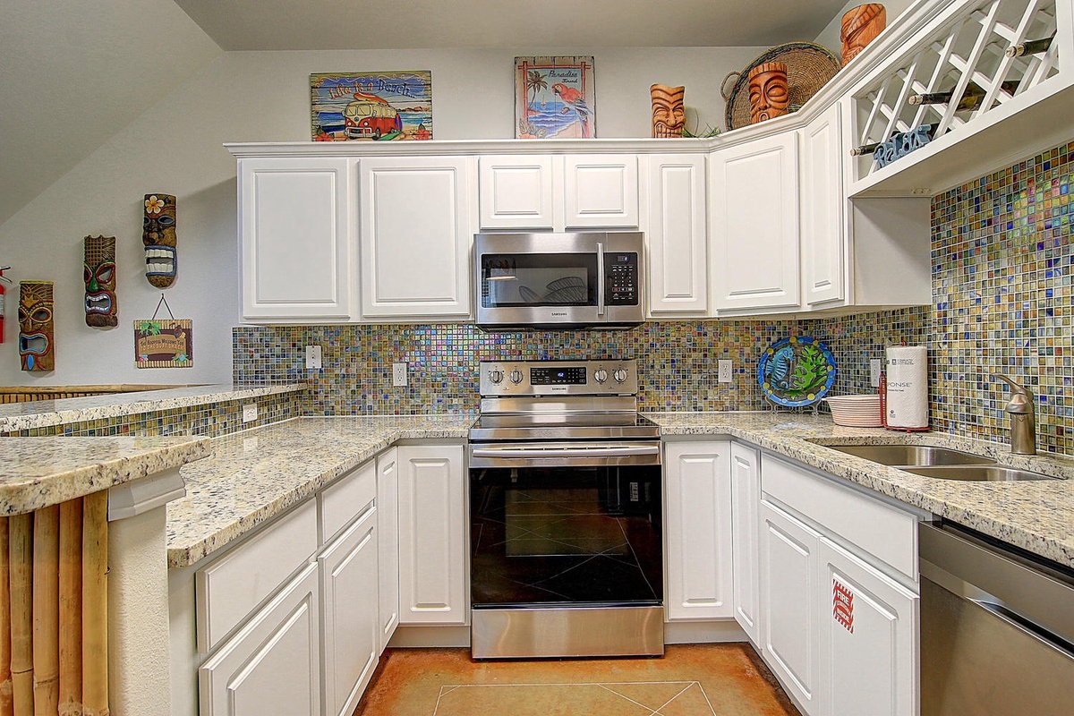 Your fully equipped kitchen awaits with granite counters, colorful mosaic backsplash, and tropical décor creating a cheerful cooking space.