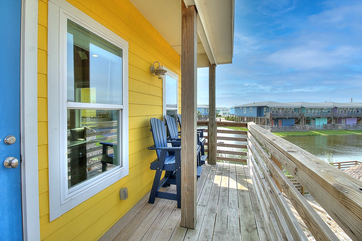 Bright beachfront cottage with covered deck and Adirondack chairs overlooking the waterfront community