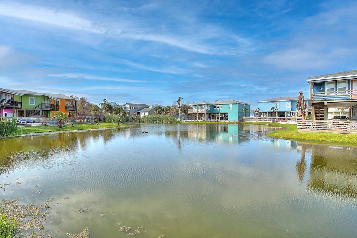 Colorful waterfront homes reflect in the peaceful lagoon, creating a picturesque coastal community setting.