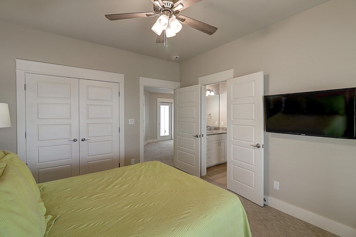 Unwind in your spacious bedroom with its cozy ceiling fan, wall-mounted TV for entertainment, and convenient en-suite access through elegant double doors.
