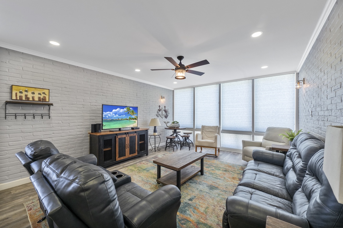 Relax in your spacious living room with plush leather seating, exposed brick walls, and floor-to-ceiling windows flooding the space with natural light.