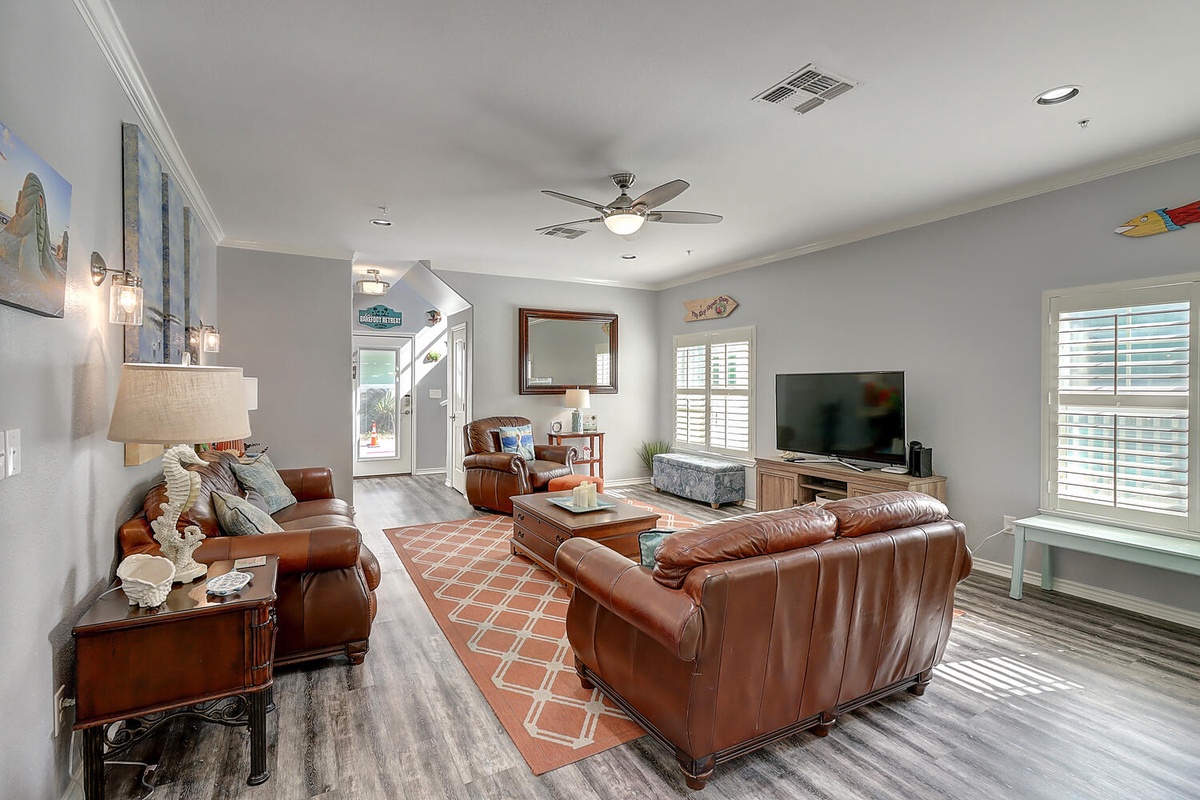 Sink into luxurious leather seating in your spacious living area, where coastal artwork and warm lighting create the perfect atmosphere for relaxing evenings together.